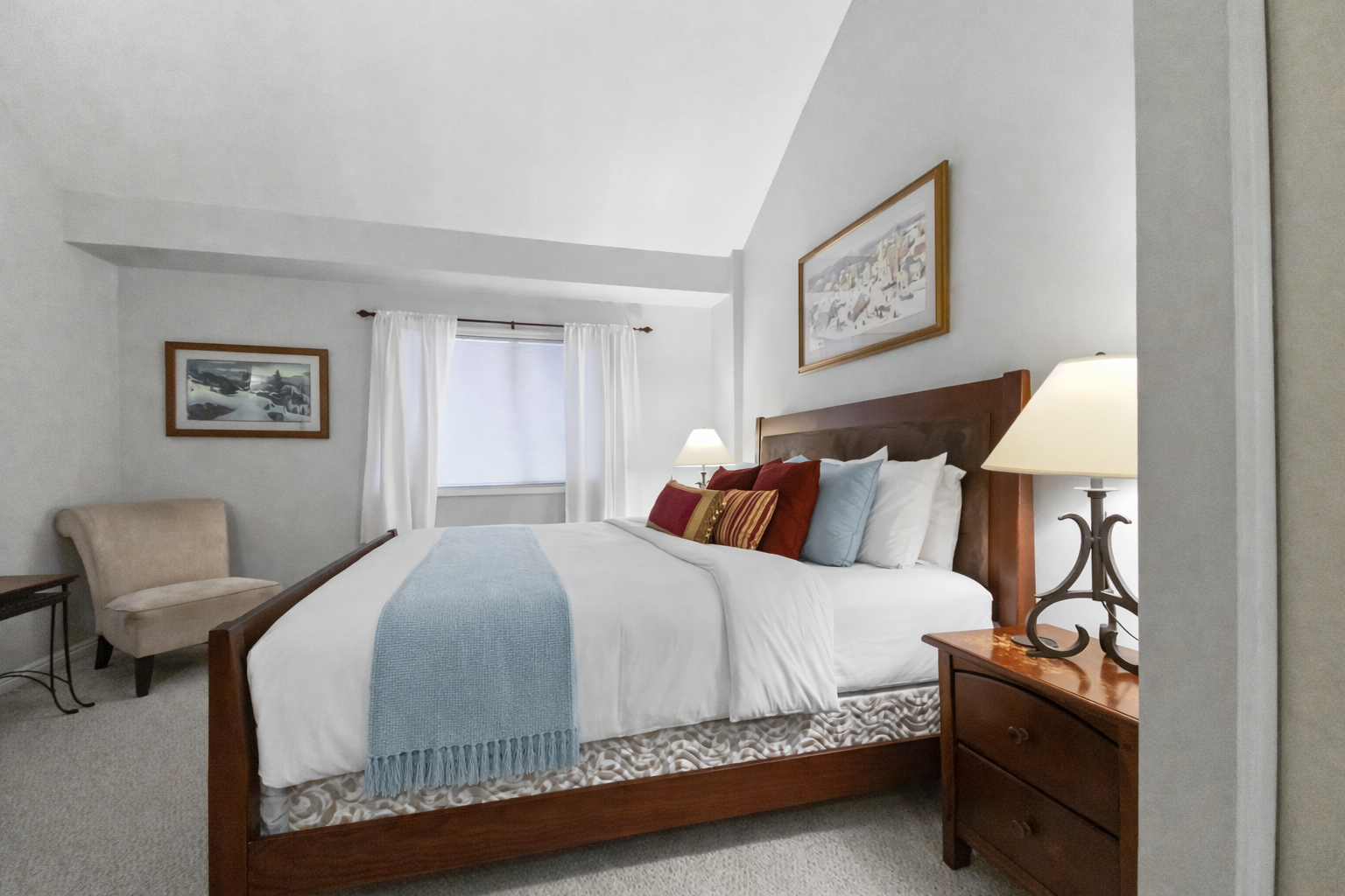 Peaceful guest bedroom featuring a comfortable bed, ceiling fan, and lovely artwork. A tranquil retreat for a restful stay in the mountains.