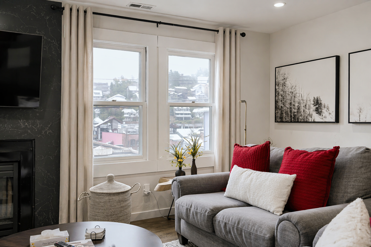 Sink into your cozy sofa with vibrant red pillows while enjoying natural light streaming through large windows in this stylish living room.
