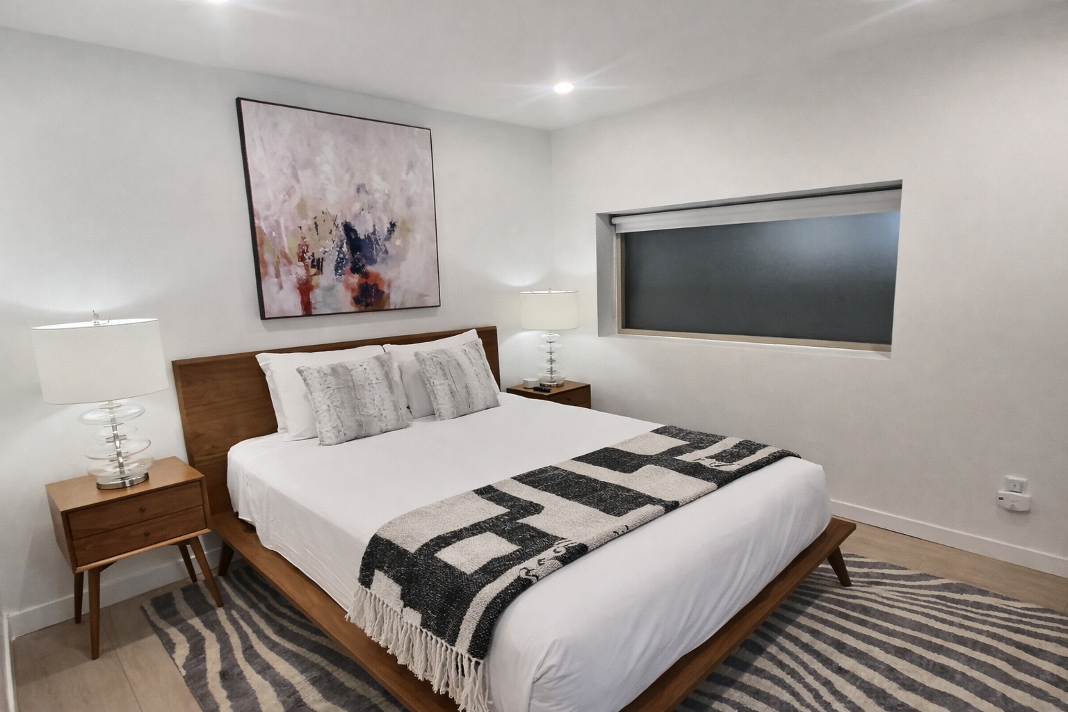 Relax in this serene, modern bedroom with a comfortable bed, ample storage, and a dedicated spin bike.