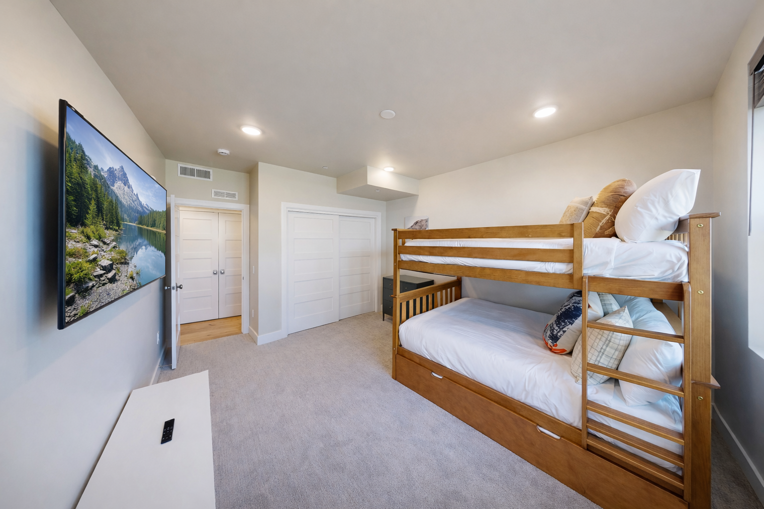 Host large groups in this modern Park City bunk room featuring a triple-tier bed, sleek grey dresser, and bright windows. The perfect year-round family alpine retreat!