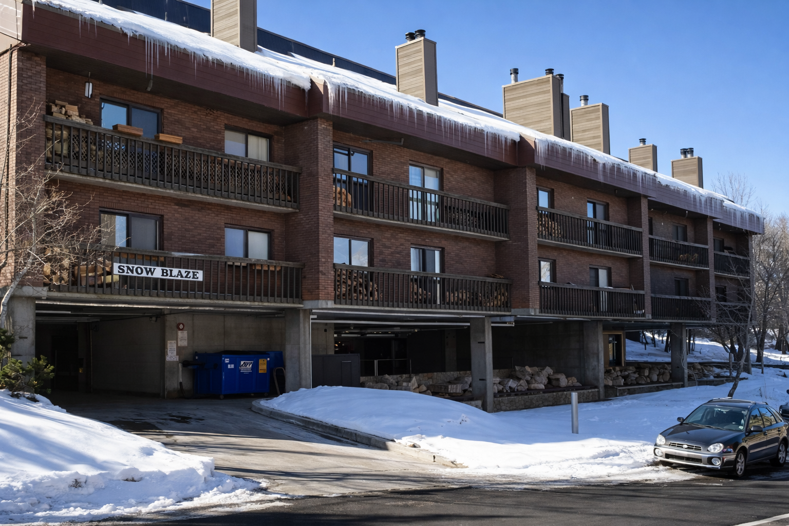 Snow Blaze building features winter charm with dramatic icicles and convenient ground-level parking in a snowy mountain setting.