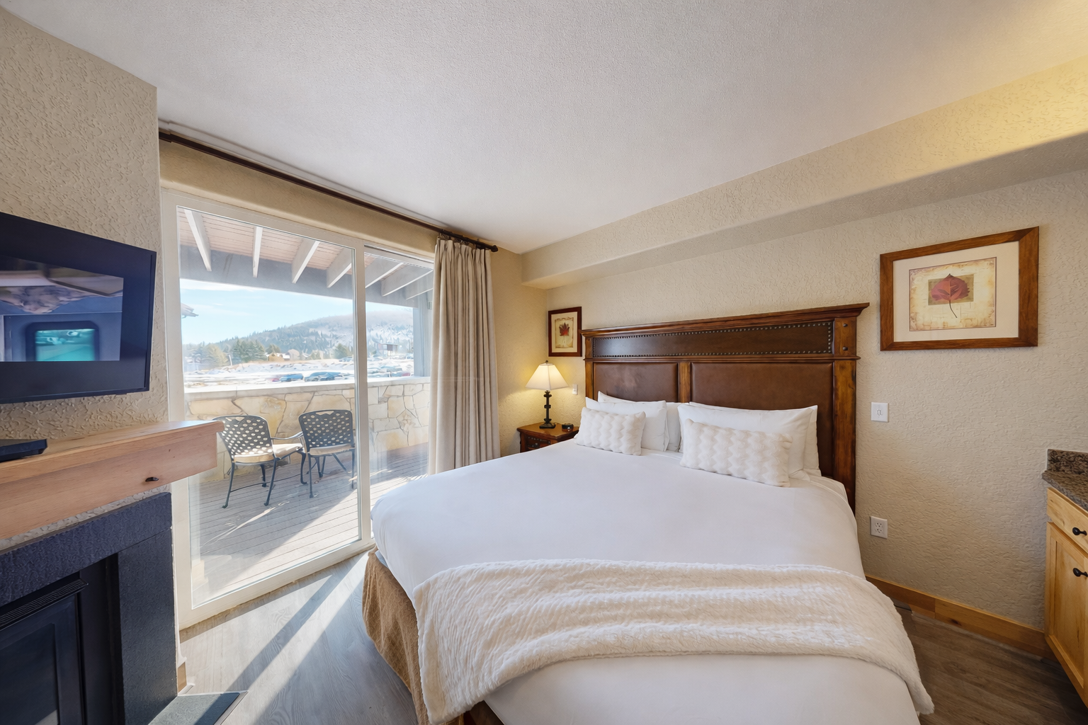 Unwind in this serene bedroom featuring a plush king-sized bed and warm wood accents. Step through sliding doors onto your private balcony to enjoy fresh air and stunning mountain views.