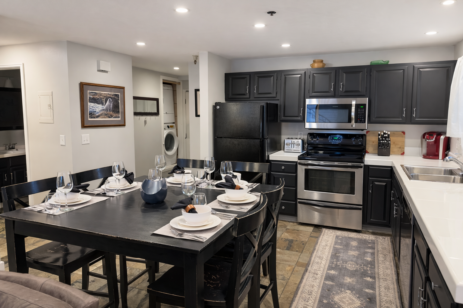Your spacious kitchen features modern dark cabinetry, stainless steel appliances, and a welcoming dining table set for memorable meals together.