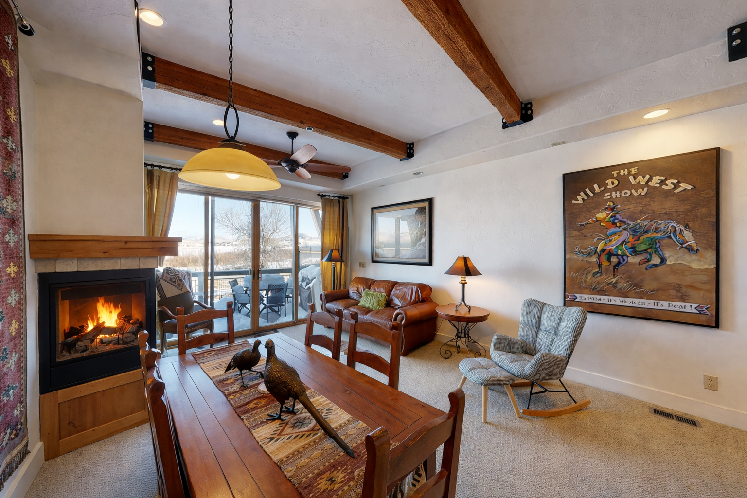 Gather around the fireplace and dining table in this inviting living space, where exposed wood beams and mountain-inspired artwork create a cozy, rustic retreat perfect for your mountain getaway.