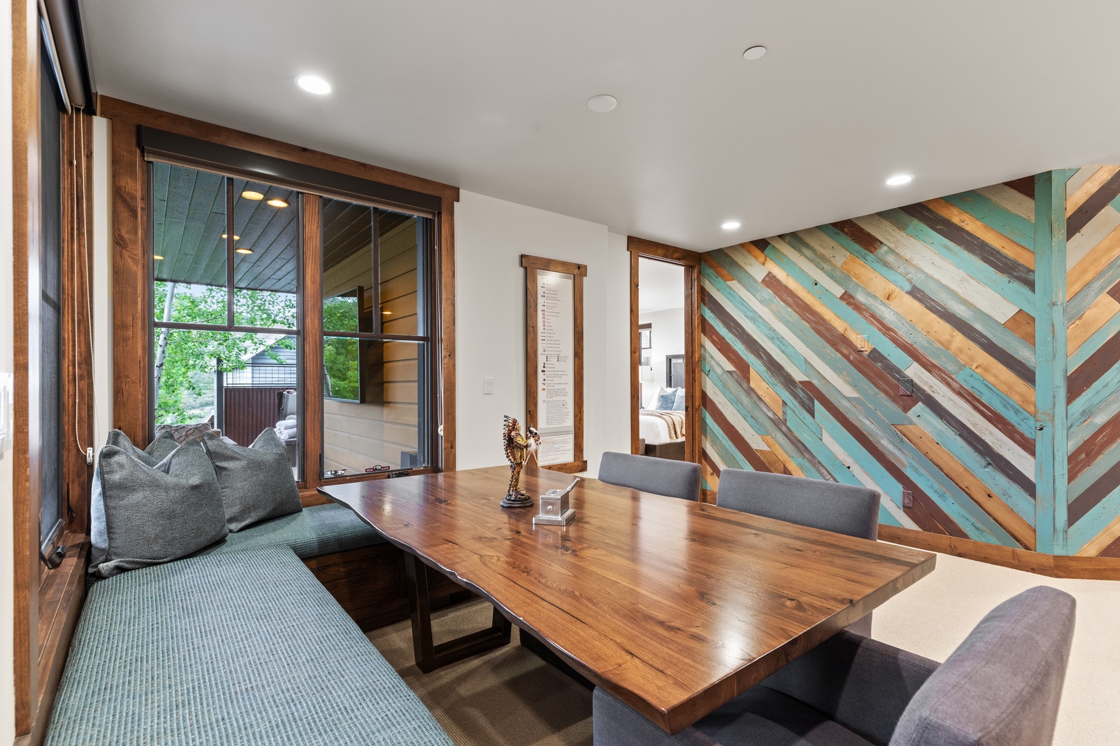 Gather around your private dining table beneath a striking reclaimed wood accent wall, where natural light and vibrant colors create an inspiring space for meals and connection.