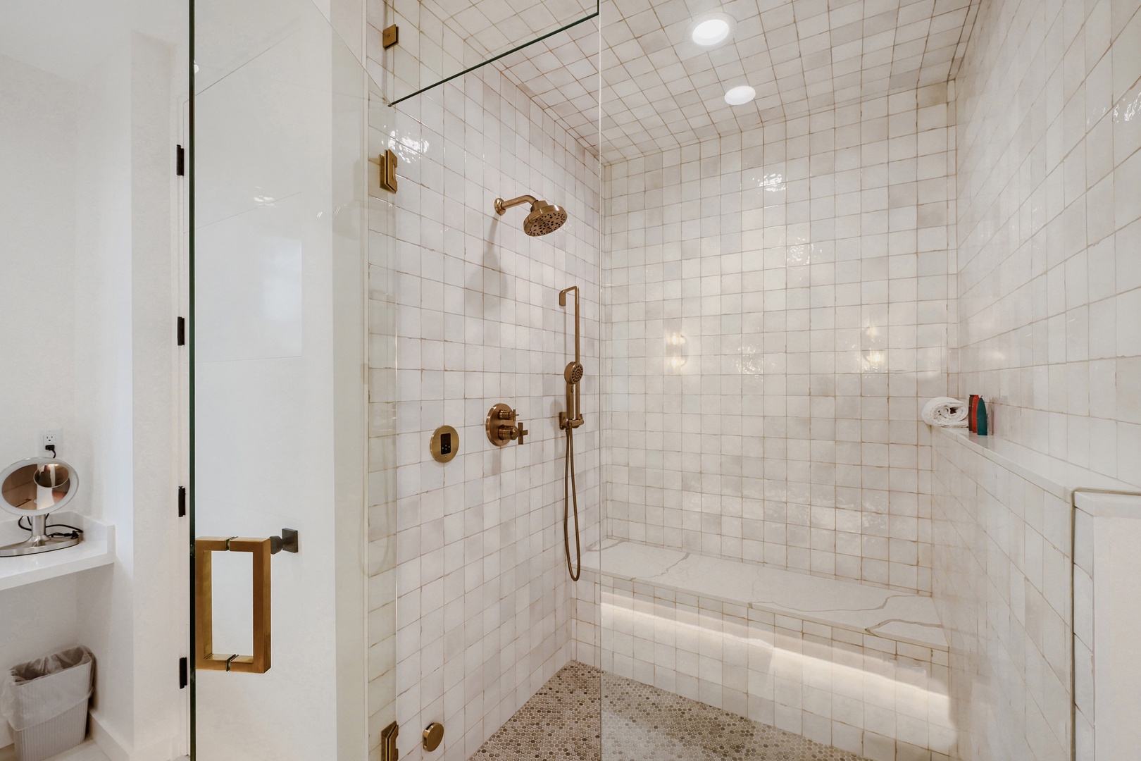 Step into your private spa-like shower featuring gleaming white tile, elegant gold fixtures, and a built-in bench—your serene escape after a day of exploring.