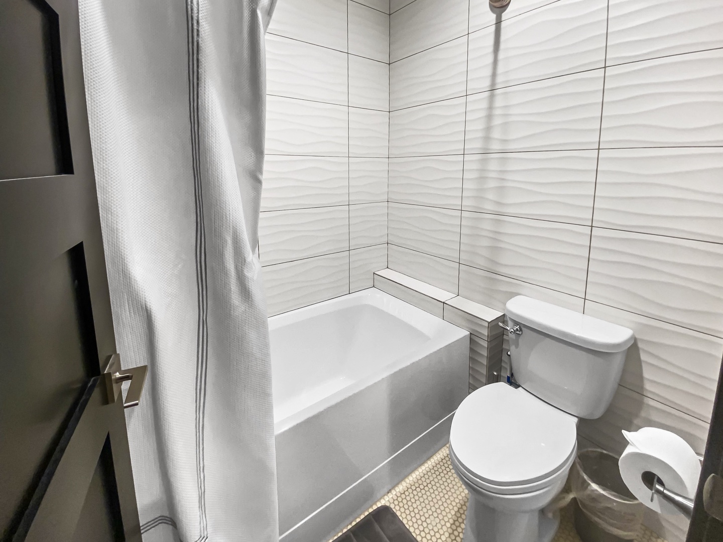 Step into your private bathroom featuring a sleek tub-shower combo and modern textured tiling. Everything you need to refresh and recharge after a day of adventure.