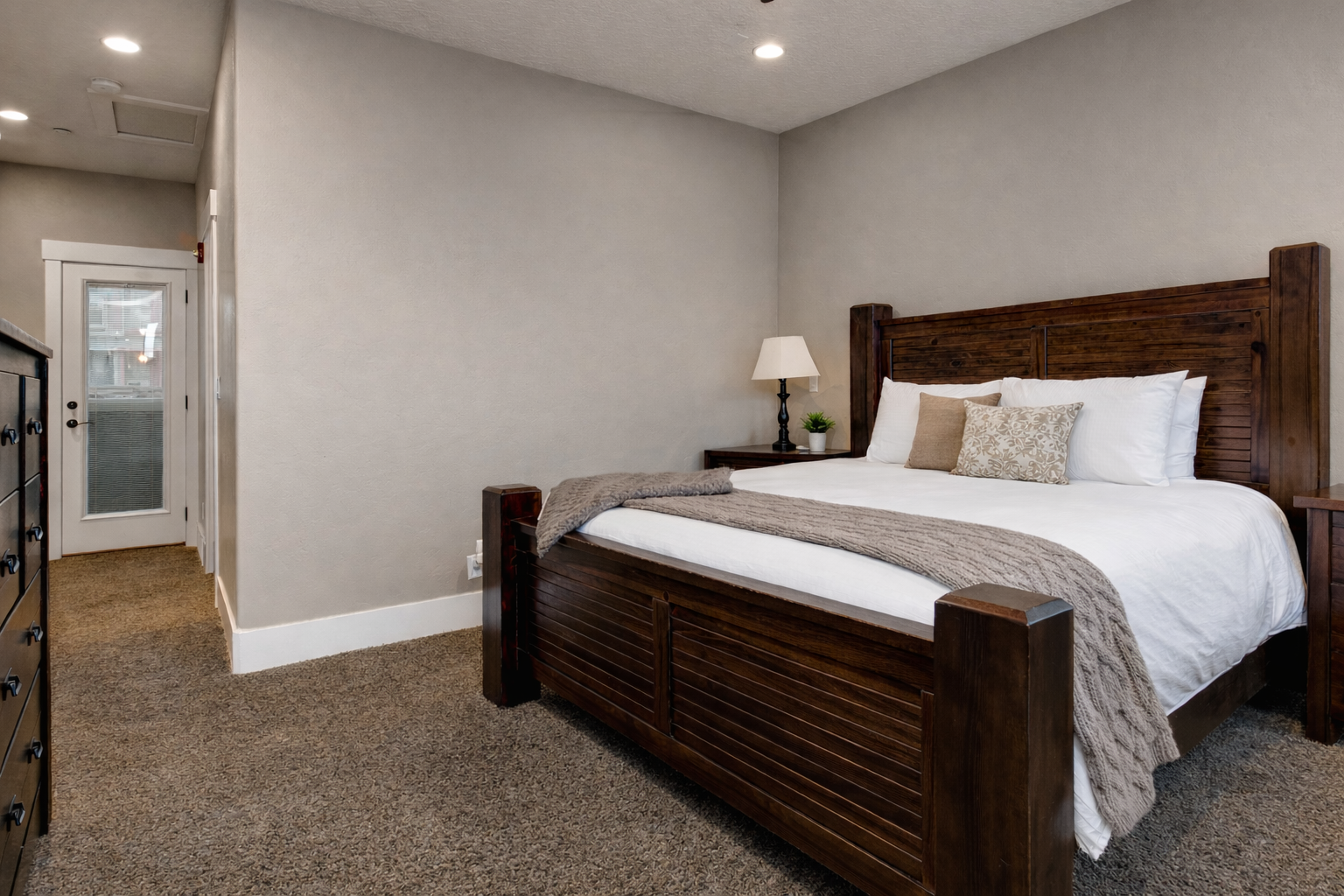 Sink into the plush king bed with crisp white linens and cozy throw blanket, perfectly positioned in your peaceful retreat.