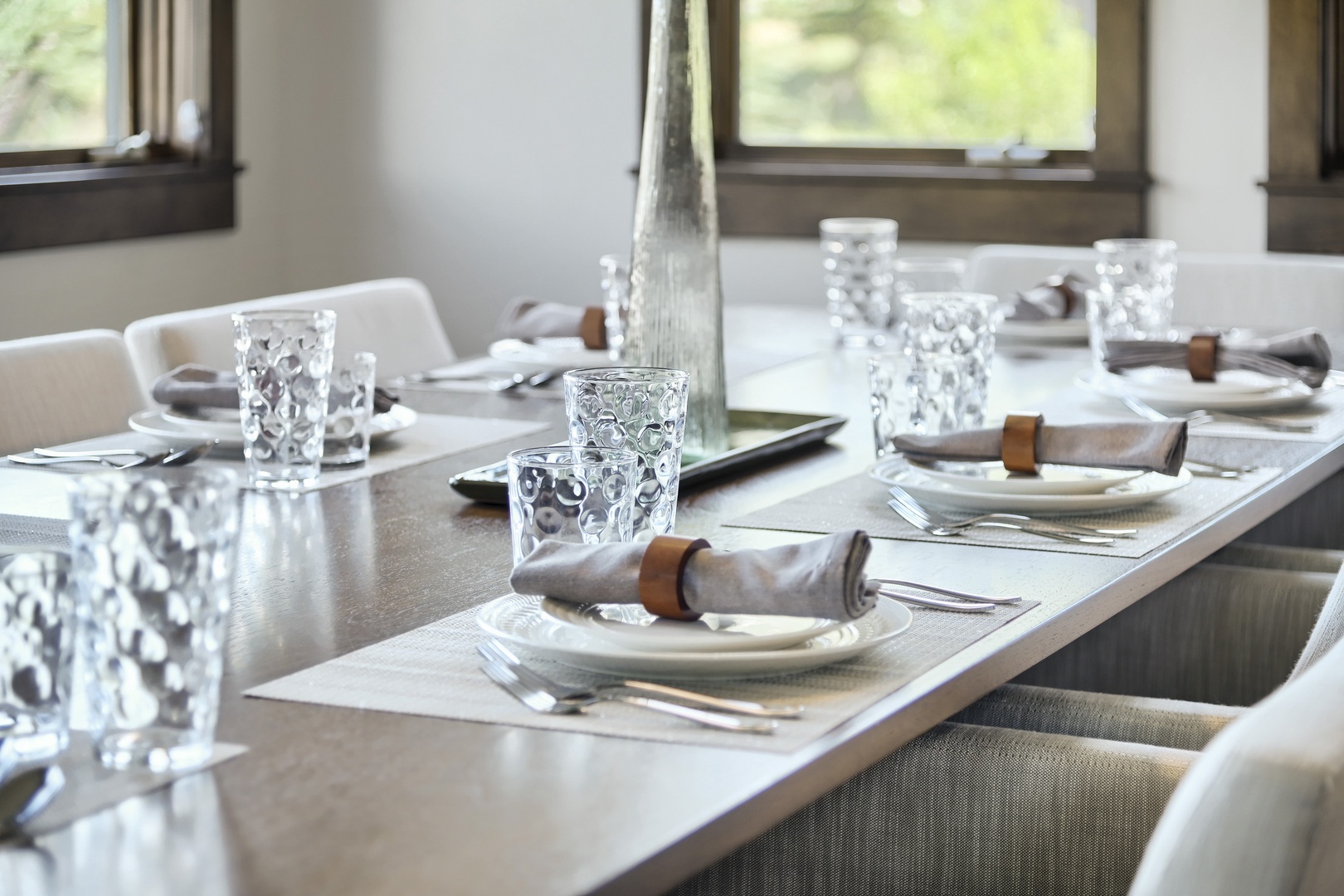Your elegant dining table is beautifully set with textured glassware and earthy napkin rings, creating a warm atmosphere perfect for memorable meals with friends and family.