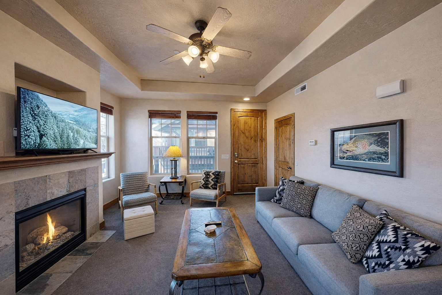 Unwind in your cozy living room with crackling fireplace, plush seating, and mountain views through sunny windows.