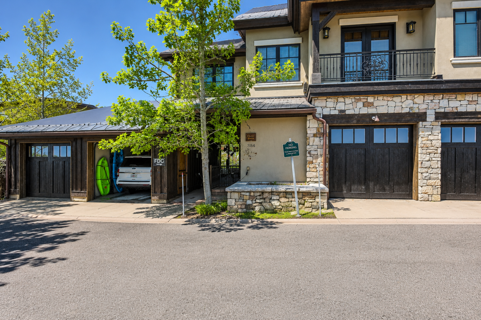 This mountain-style property features stone and stucco architecture, private garage parking, and balconies overlooking the surrounding area. The entrance is clearly marked for easy arrival.