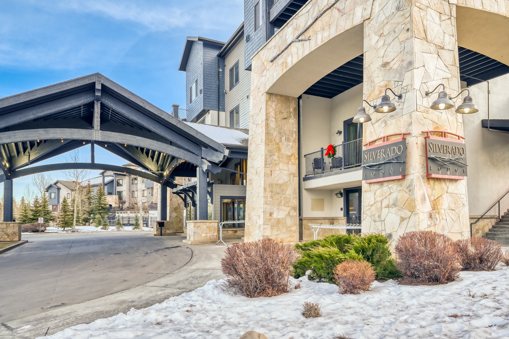 Mountain resort entrance with stone facade and distinctive covered arrival area surrounded by winter landscaping.
