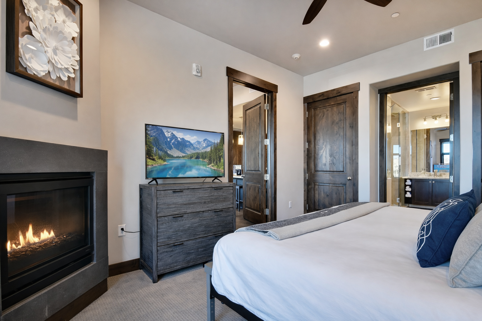 Unwind in your cozy bedroom where mountain views on the TV complement the warm fireplace glow and rustic wood details.