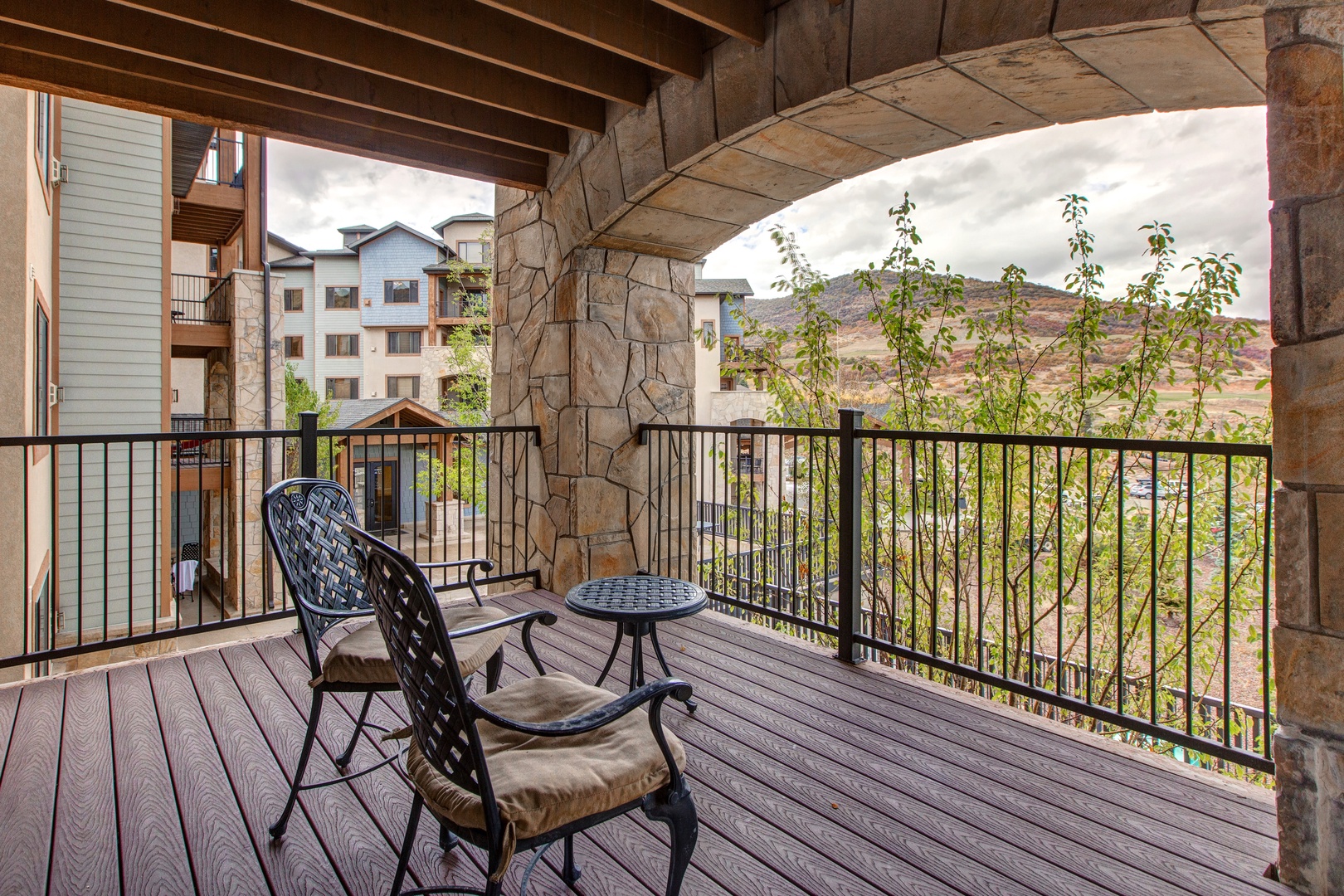 Sip your morning coffee or enjoy an evening drink on the private balcony, featuring comfortable seating, a charming stone facade, and a picturesque view of the surrounding landscape.
