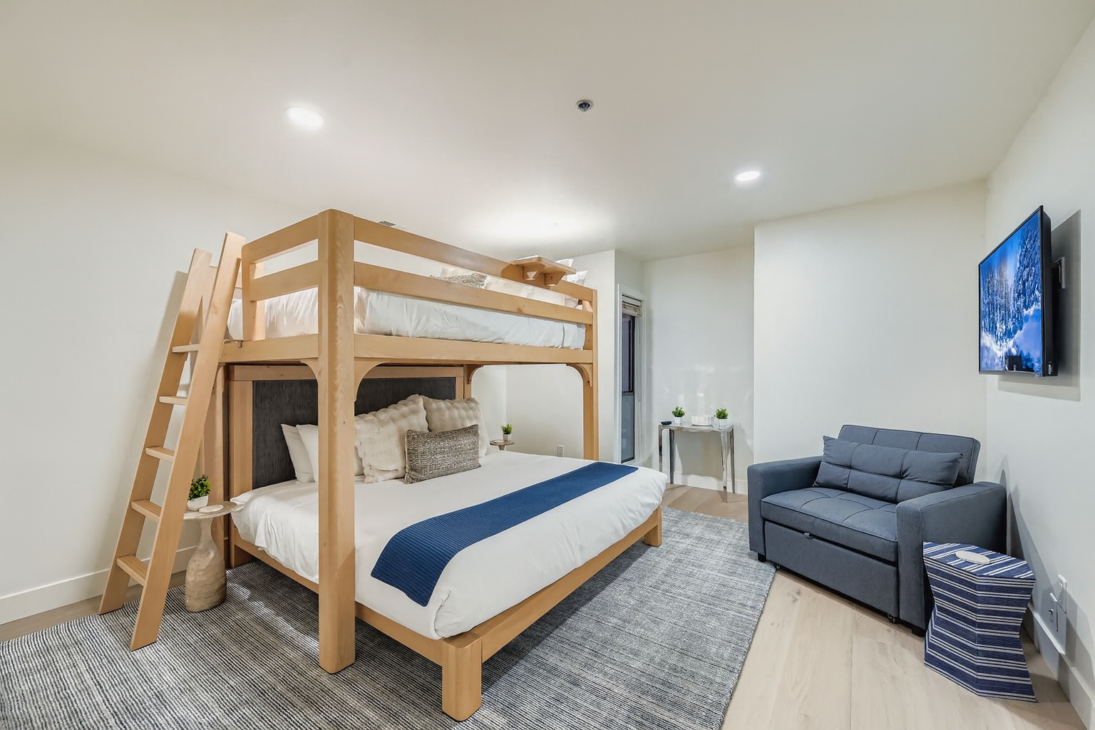 Your modern bedroom features a stylish bunk bed setup with crisp white linens and a comfortable seating area where you can relax and unwind.