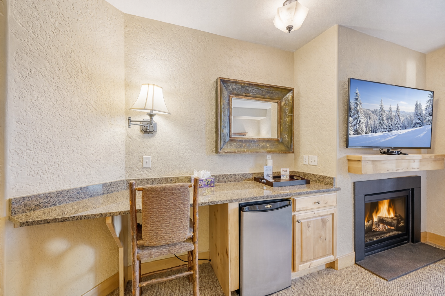 Perfect for business or leisure! This efficient workspace includes a built-in desk, mini-fridge, and cozy lighting, all nestled next to a warm fireplace.