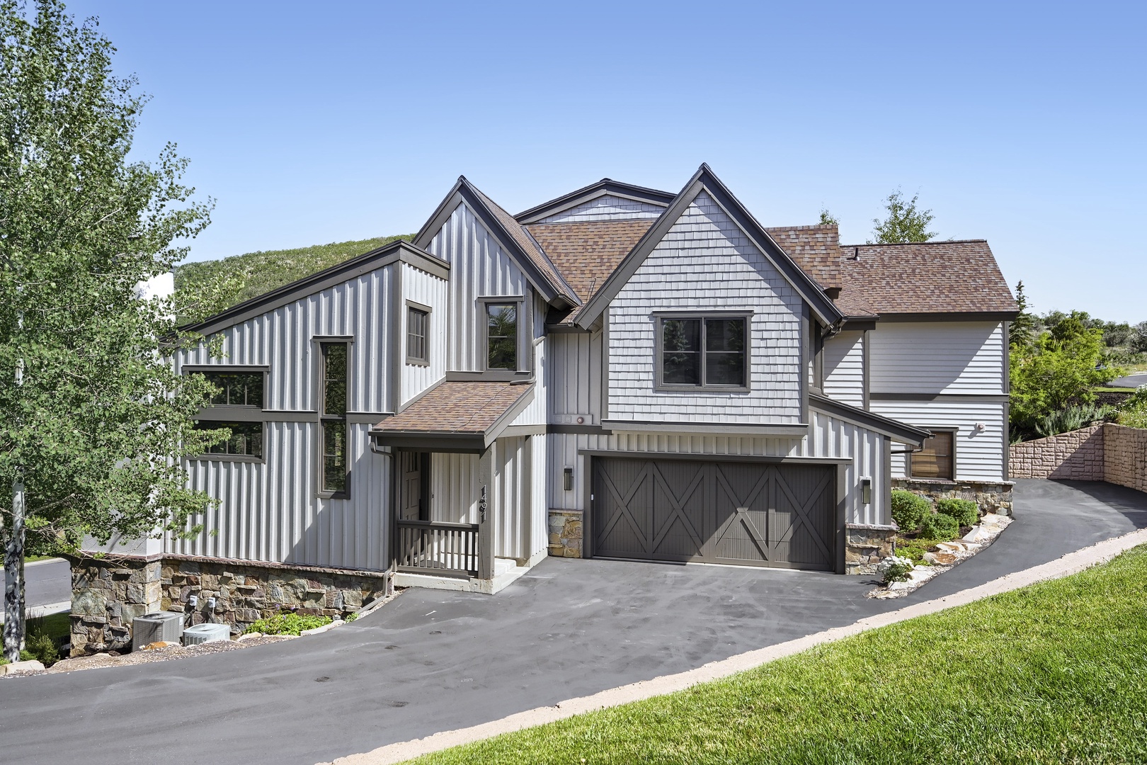 A charming mountain retreat featuring distinctive striped siding and surrounded by lush greenery, this property combines architectural character with natural beauty in a peaceful hillside setting.