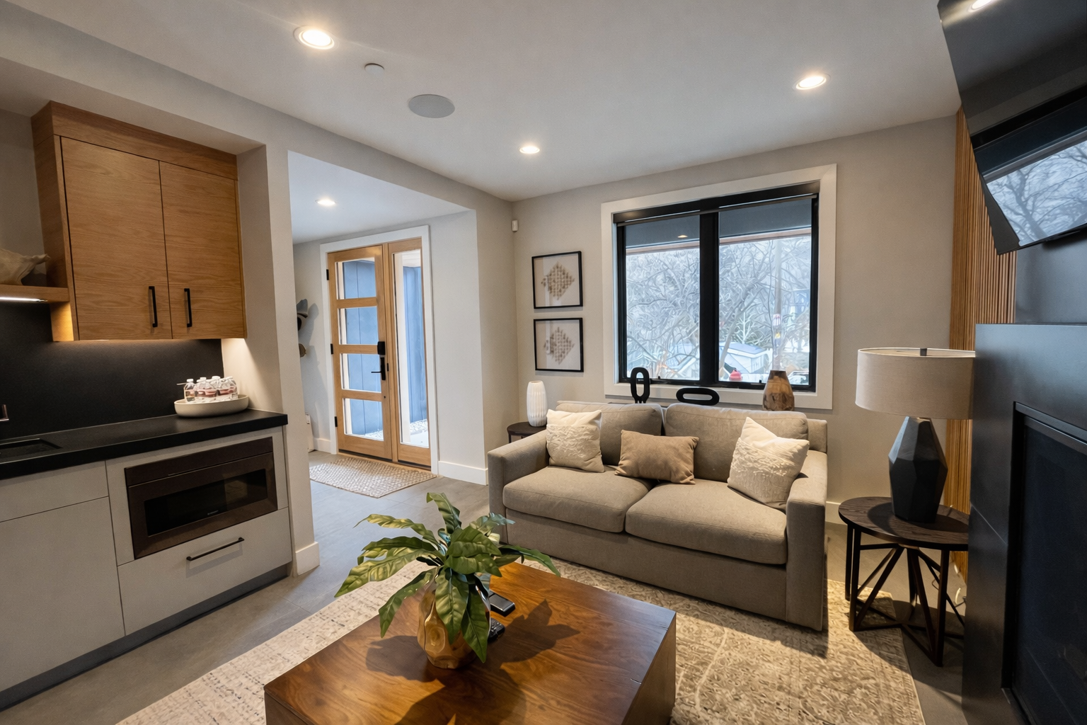 Your modern open-plan space blends kitchen and living seamlessly, with warm wood accents and a cozy sofa perfect for relaxing after exploring.