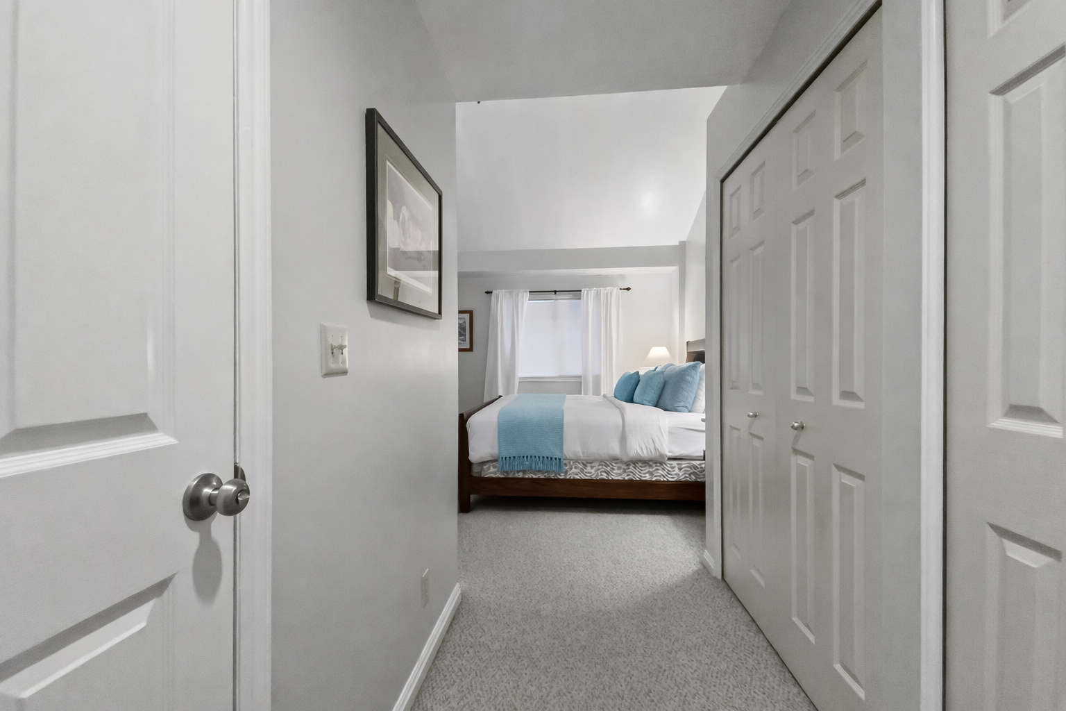 Step into your private hallway leading to a peaceful bedroom retreat with cozy blue accents and plush bedding.