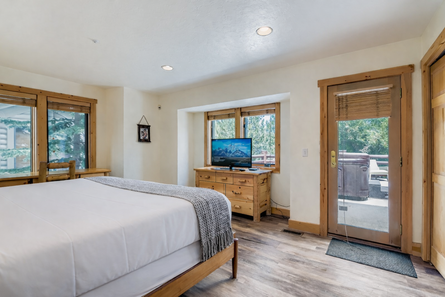 Your bright bedroom opens to an outdoor area, featuring a cozy bed, entertainment center, and warm wood accents throughout.
