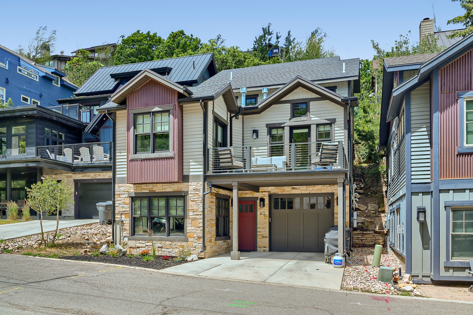 This modern mountain home features a spacious balcony and stylish architecture, nestled in a quiet residential neighborhood surrounded by greenery and neighboring properties.