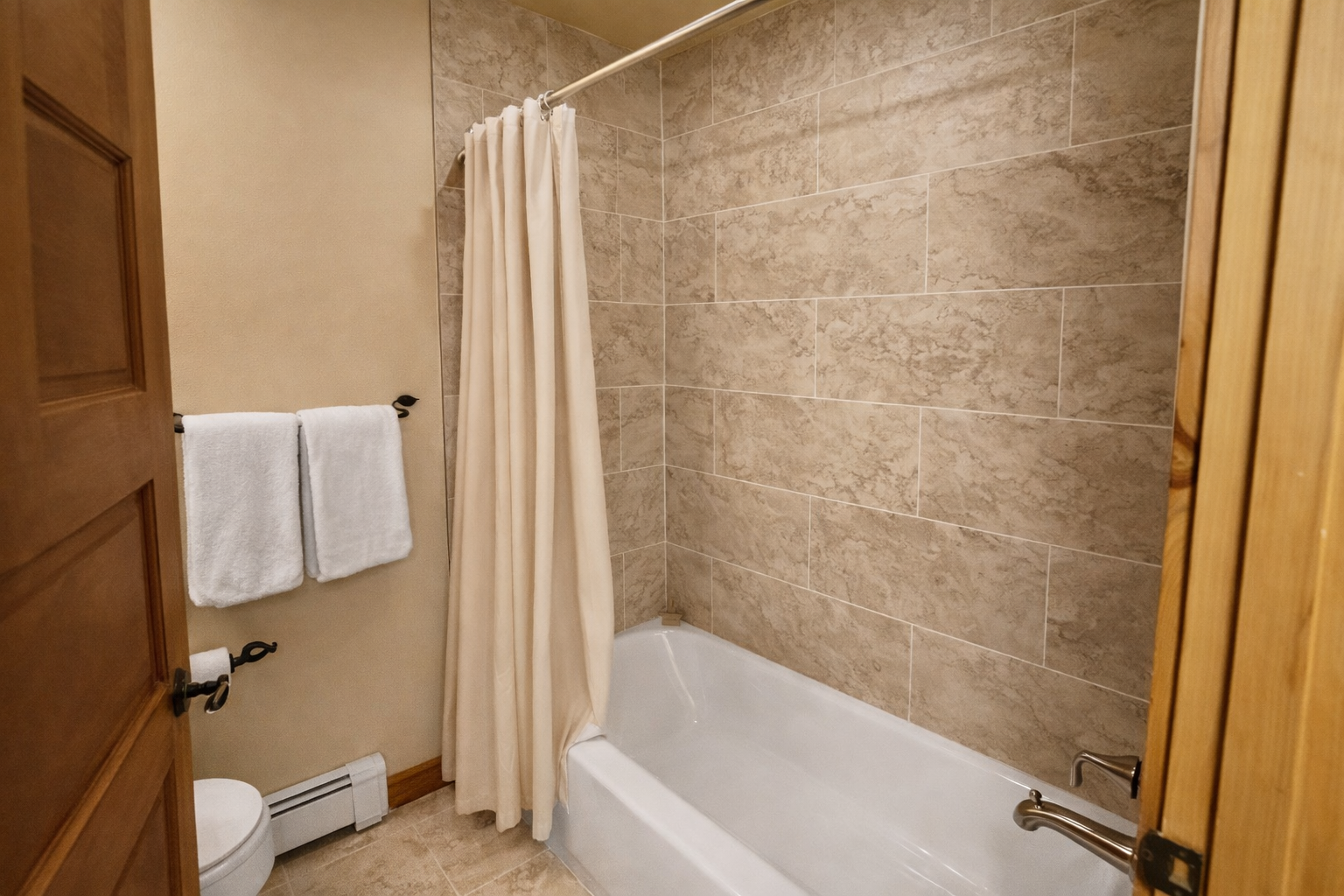 Your private bathroom features elegant stone-tiled walls, a deep soaking tub, and fresh towels ready for your relaxing retreat.
