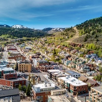 An aerial view capturing the property's location in a vibrant mountain town, surrounded by historic buildings and forested hills.