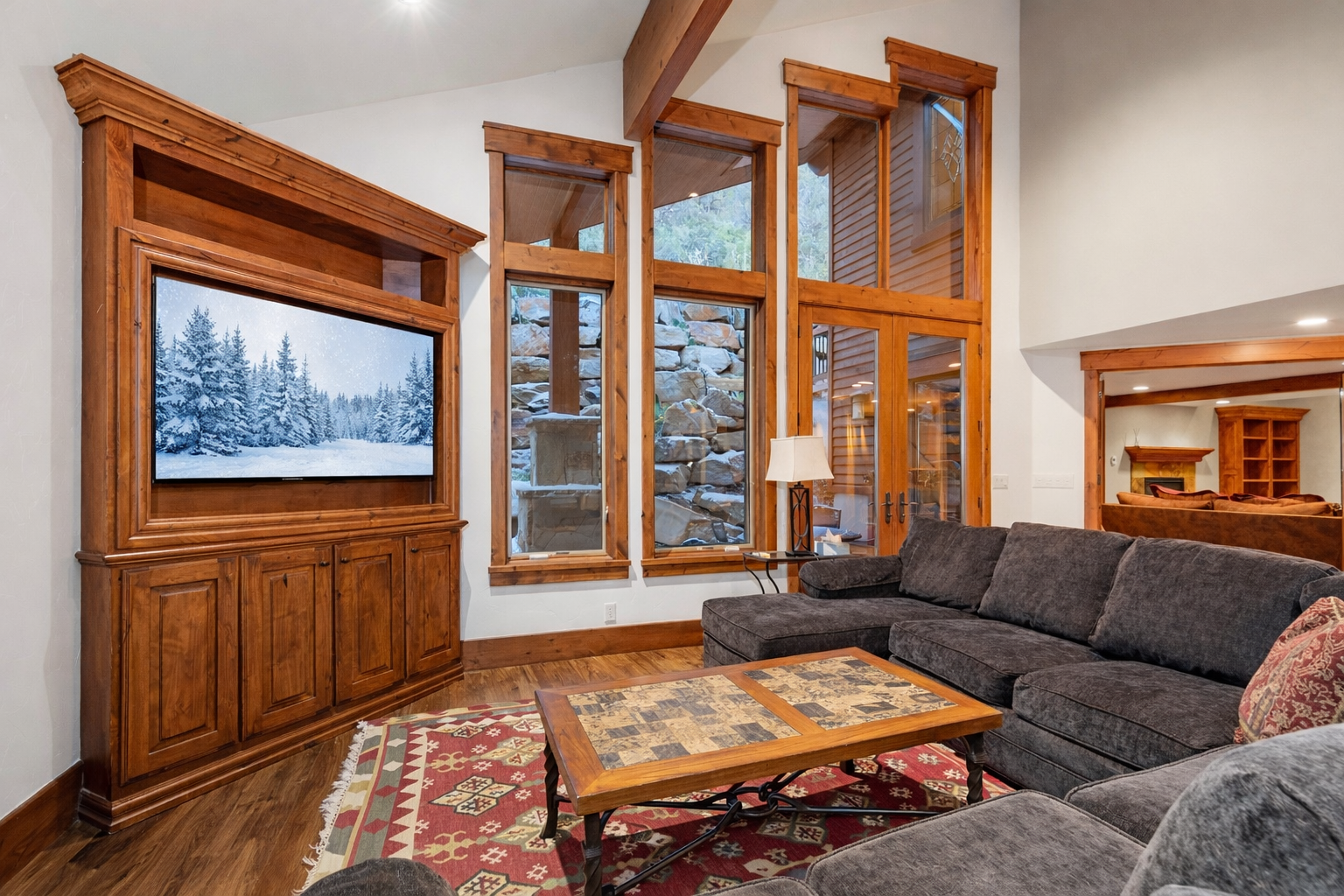 Relax in our cozy living room featuring a large sectional sofa, big-screen TV, and stunning mountain views through the expansive windows.