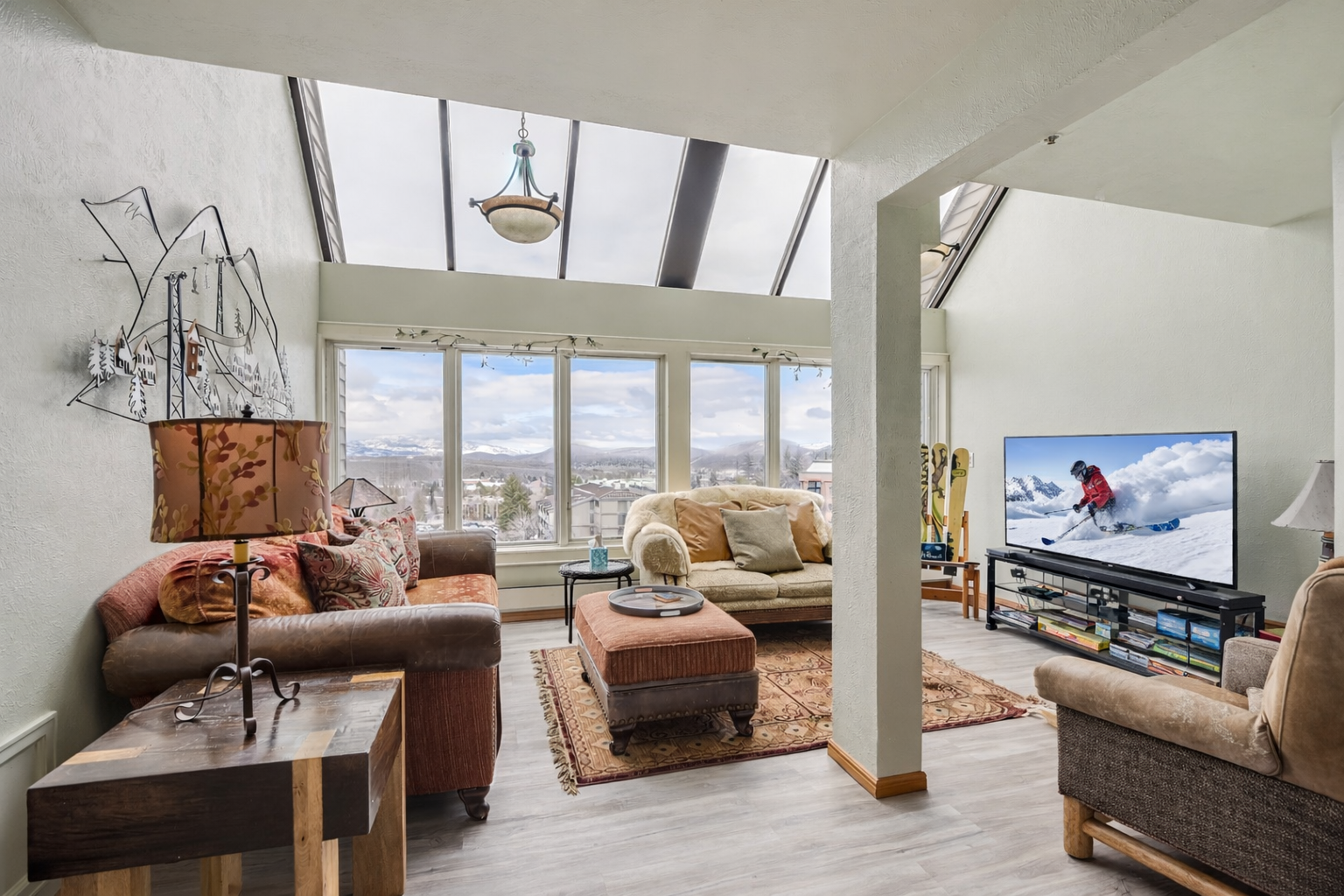 Bright, open-concept living area with large windows, scenic views, skylights, and cozy seating.