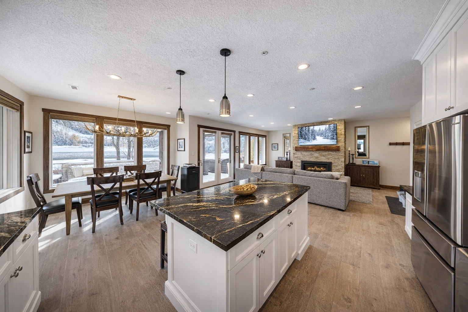 Imagine cooking in this stunning open-concept space, where a gourmet kitchen flows seamlessly into a cozy living area. Large windows frame snowy mountain views, filling your mornings with natural light and peaceful scenery.