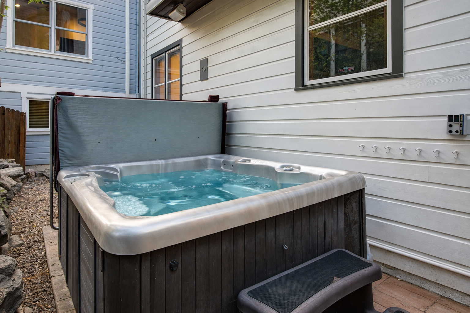 Soak away stress in your private hot tub, nestled between homes with warm bubbling water ready for relaxation.