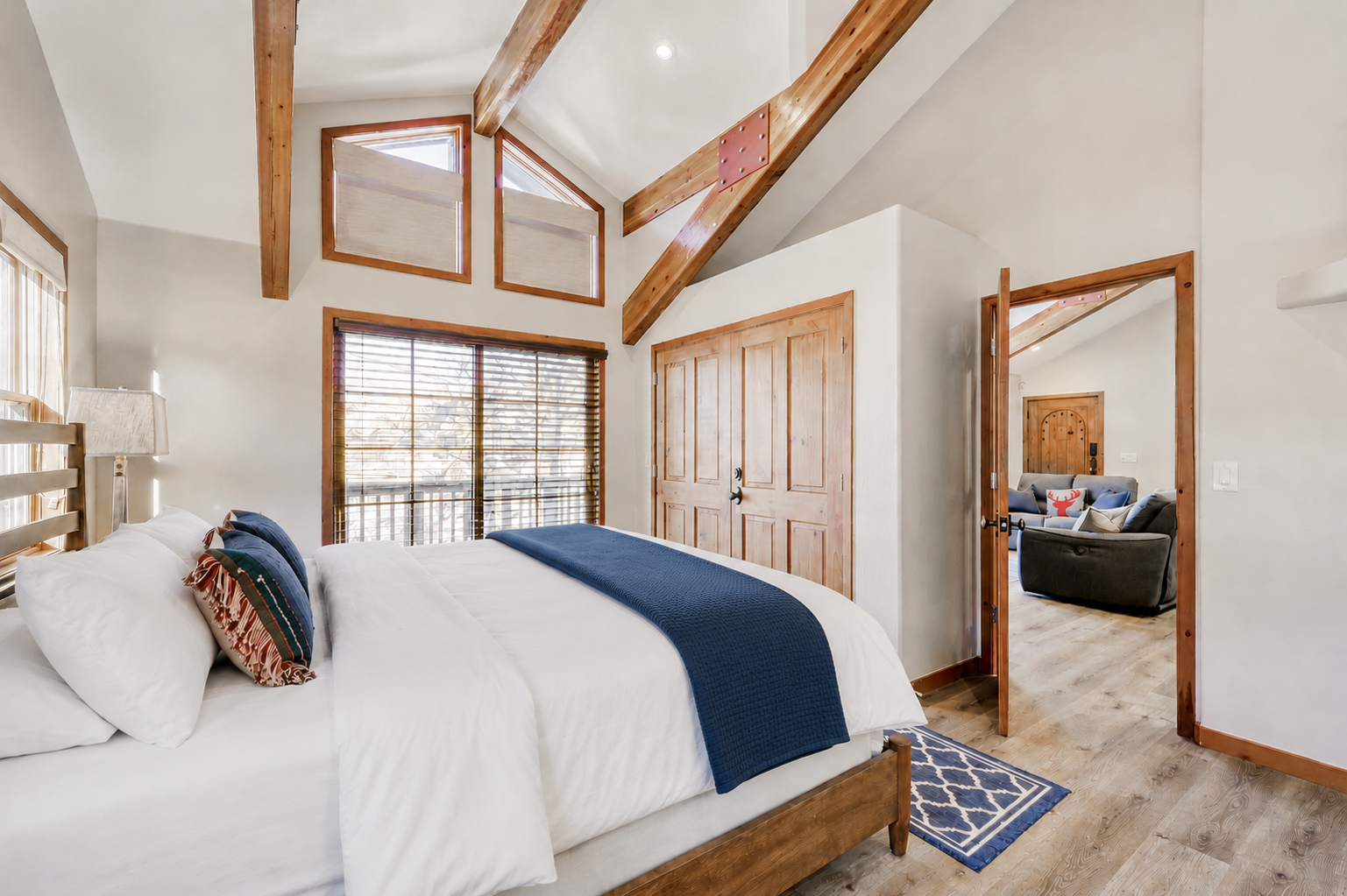 Rest easy in your bright and airy bedroom, where vaulted ceilings, exposed wooden beams, and large windows create a serene mountain retreat with beautiful natural light.