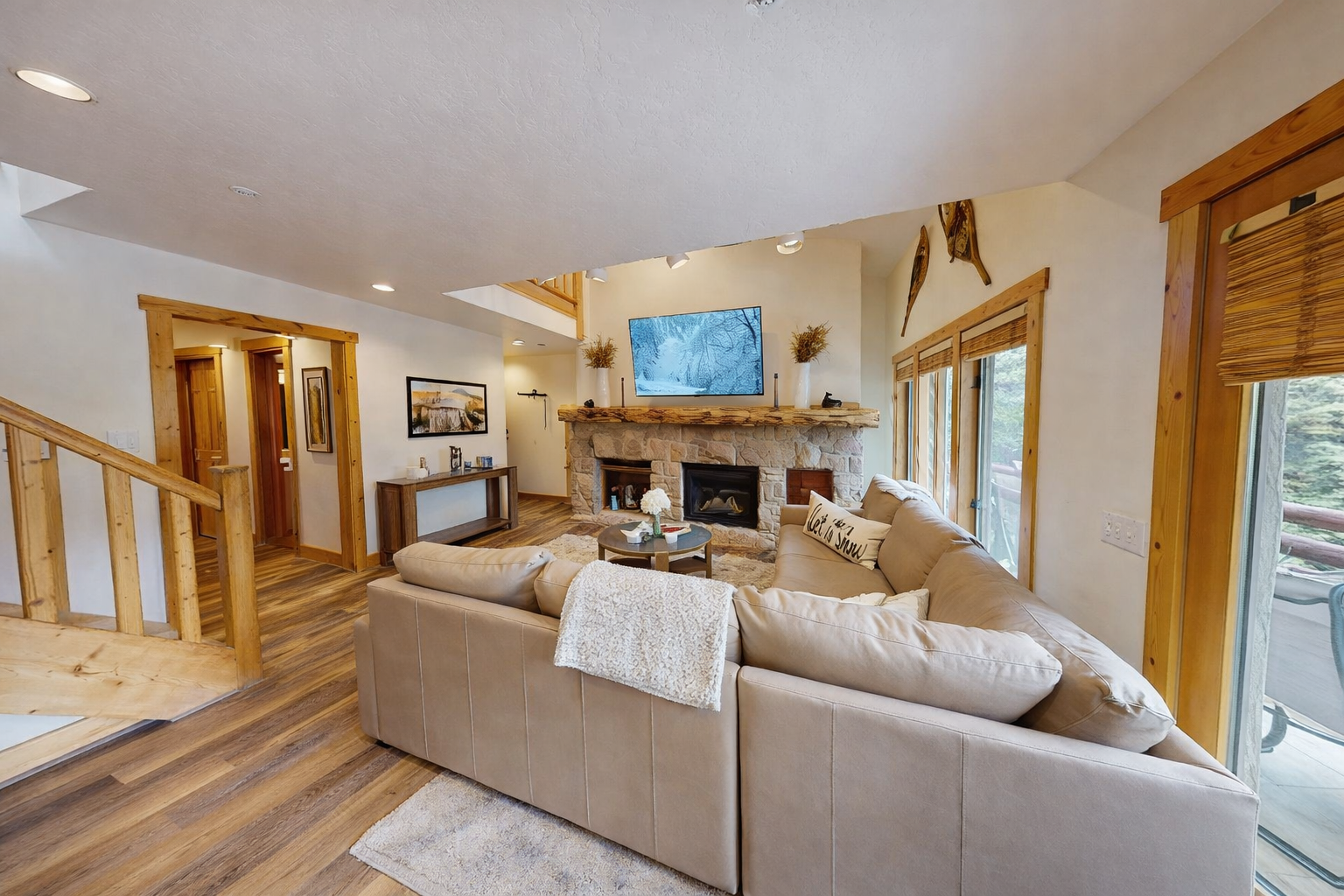 Unwind in this spacious living room where plush seating surrounds a stunning stone fireplace, perfect for cozy evenings with mountain views through large windows.