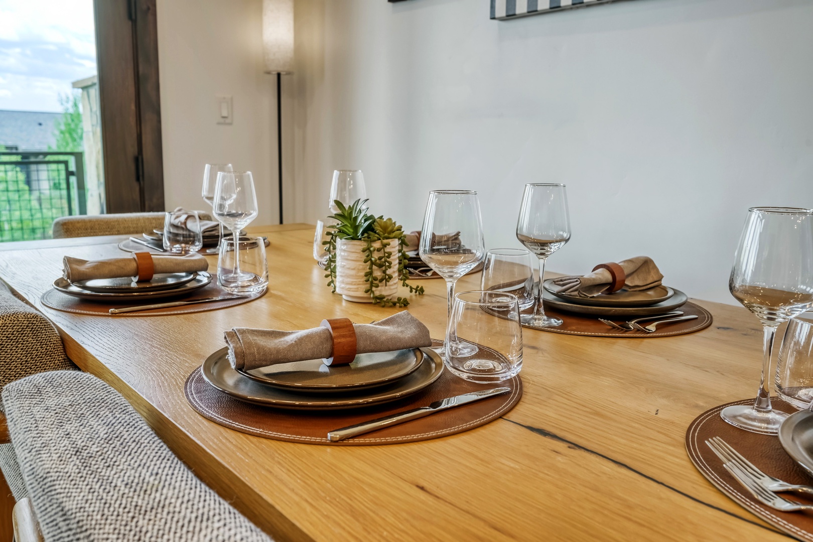 Gather around this warm wood table for memorable meals, with modern place settings, gleaming glassware, and soft natural light welcoming you to dine together in comfort and style.