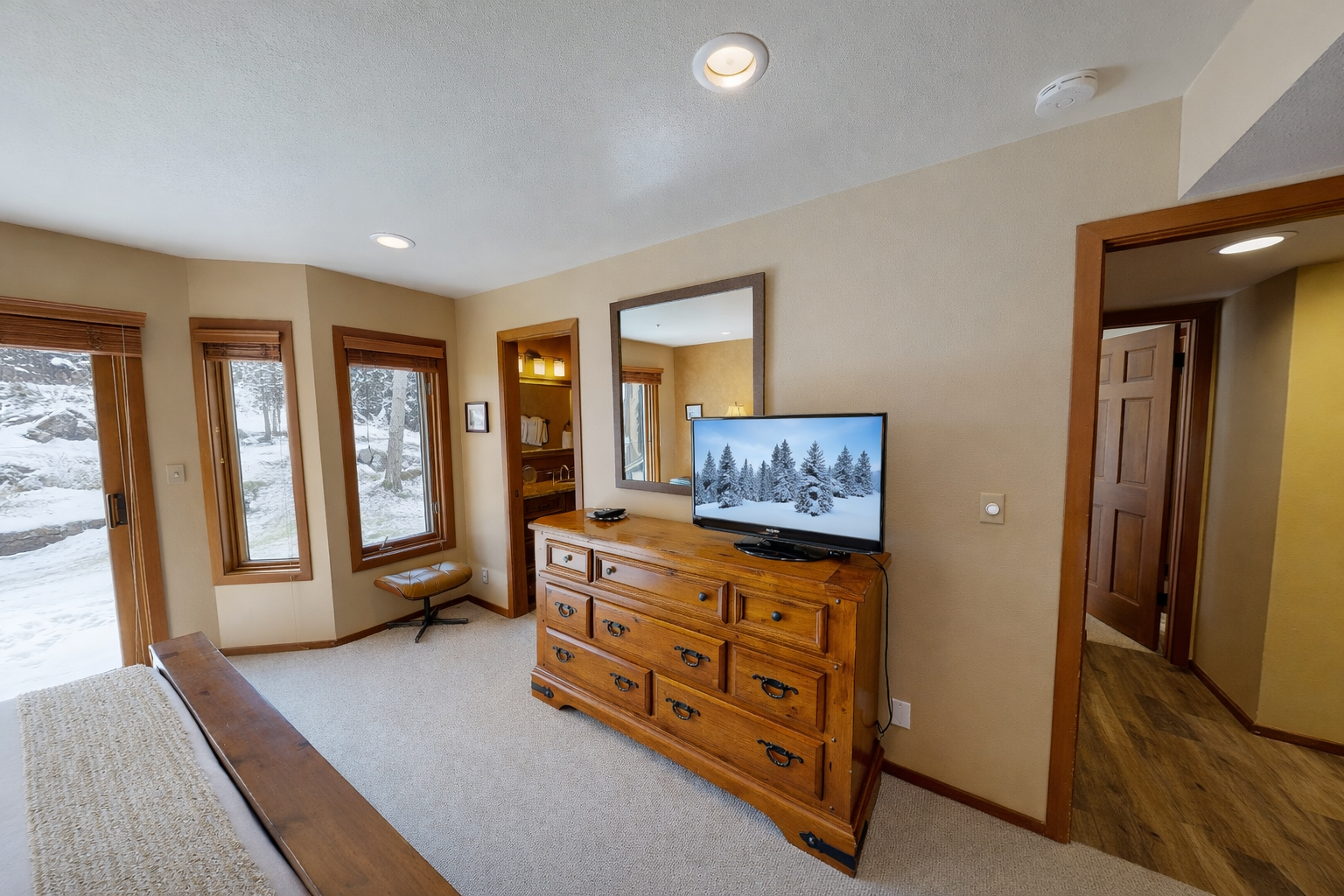 Drift off peacefully in your cozy bedroom overlooking a serene natural landscape through expansive windows.