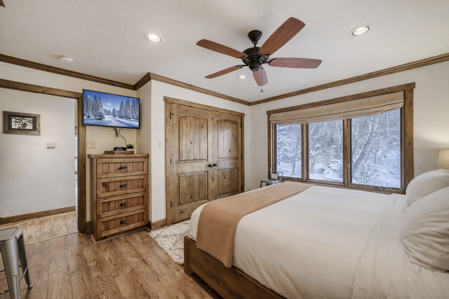 Wake up to stunning winter views through your bedroom windows, where rustic wood furnishings and cozy linens create the perfect mountain retreat sanctuary.