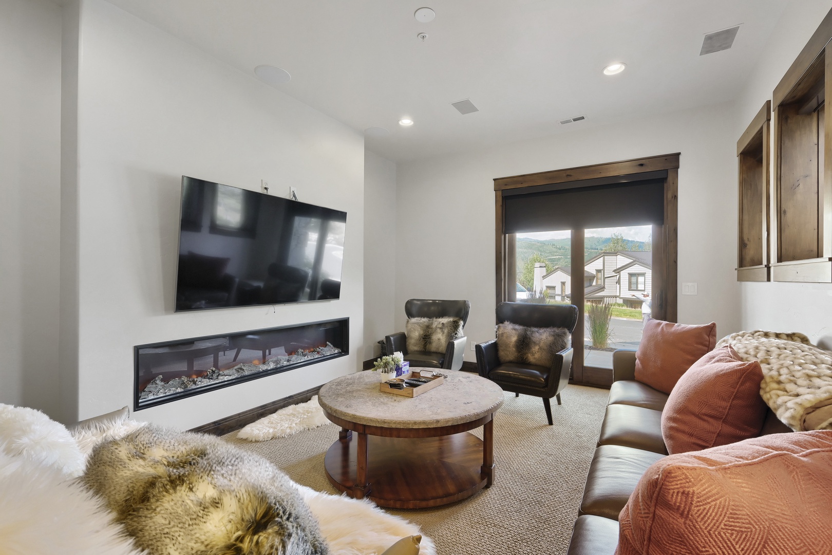Sink into plush leather seating and let the crackling fireplace set the mood for your mountain getaway. Natural light streams through the window, inviting you to unwind in comfort.