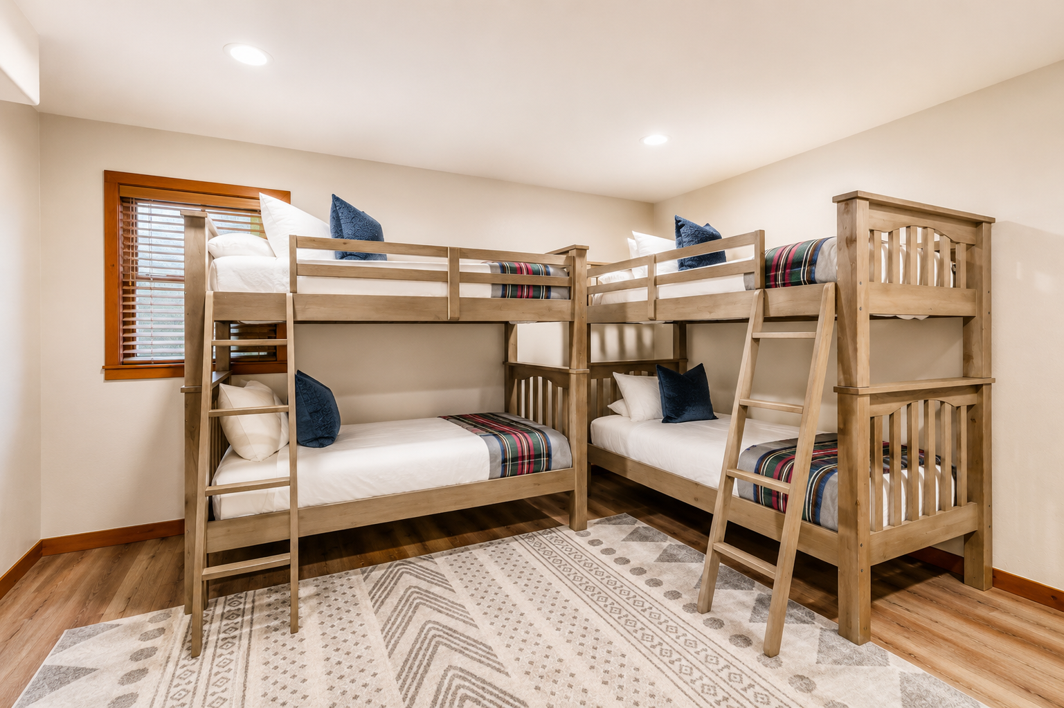 Your group will love this cheerful bunk room, where everyone gets their own cozy bed. Plaid accents and blue pillows add charm, while warm wood floors and soft lighting create a welcoming retreat.