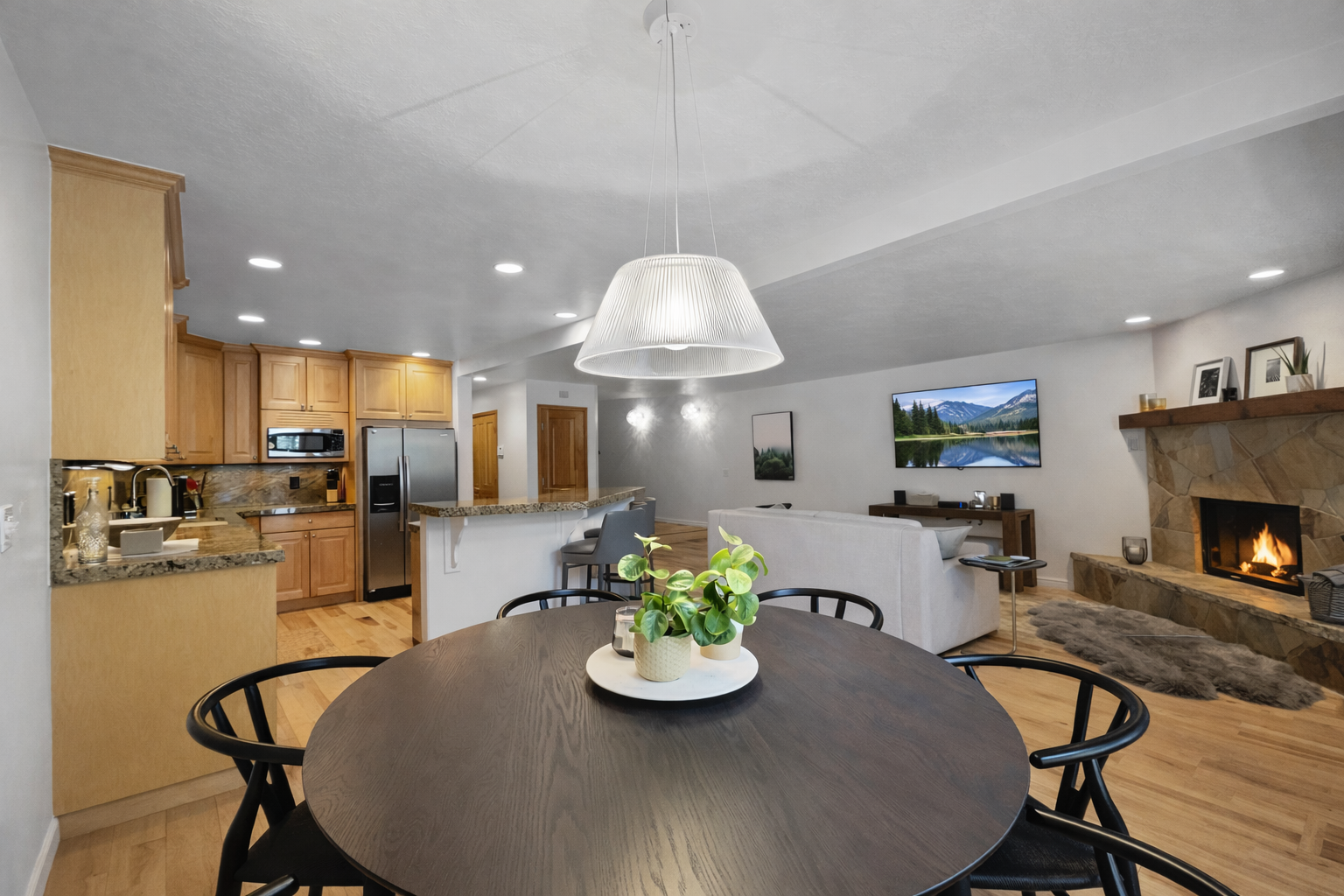 Gather around the sleek dining table while your crackling fireplace sets a cozy mood and natural light streams through windows.