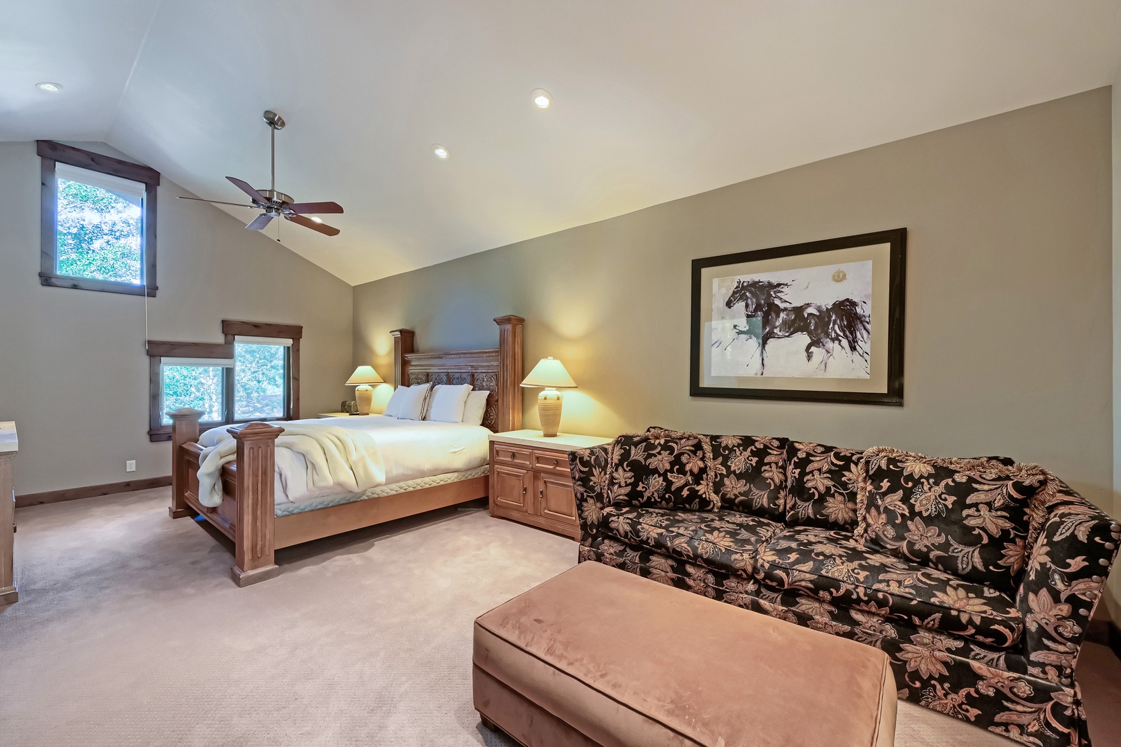 Sink into this roomy retreat featuring a rustic wood bed, cozy sofa with ottoman, and vaulted ceilings that create an airy, peaceful vibe for your mountain getaway.
