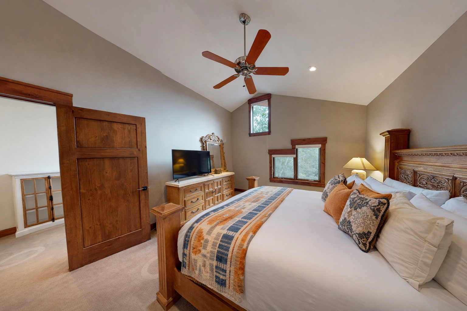 Unwind in your spacious bedroom featuring rich wood furnishings, a cozy ceiling fan, and crisp linens that promise restful nights.