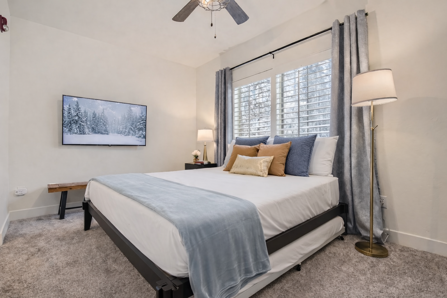 Relax in this bright, modern bedroom featuring a plush king-size bed, sleek dark wood furniture, and a large flat-screen TV. A serene mountain retreat for your next Park City adventure.