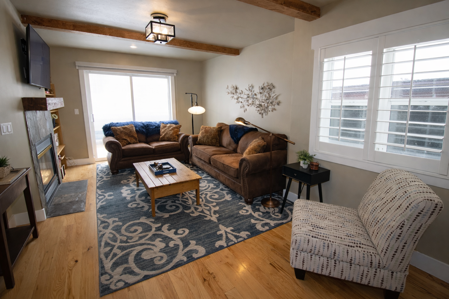 Relax in this cozy mountain retreat featuring a warm fireplace, rustic wooden accents, and plush seating. Enjoy modern amenities like a wall-mounted TV and large windows with bright, natural light.