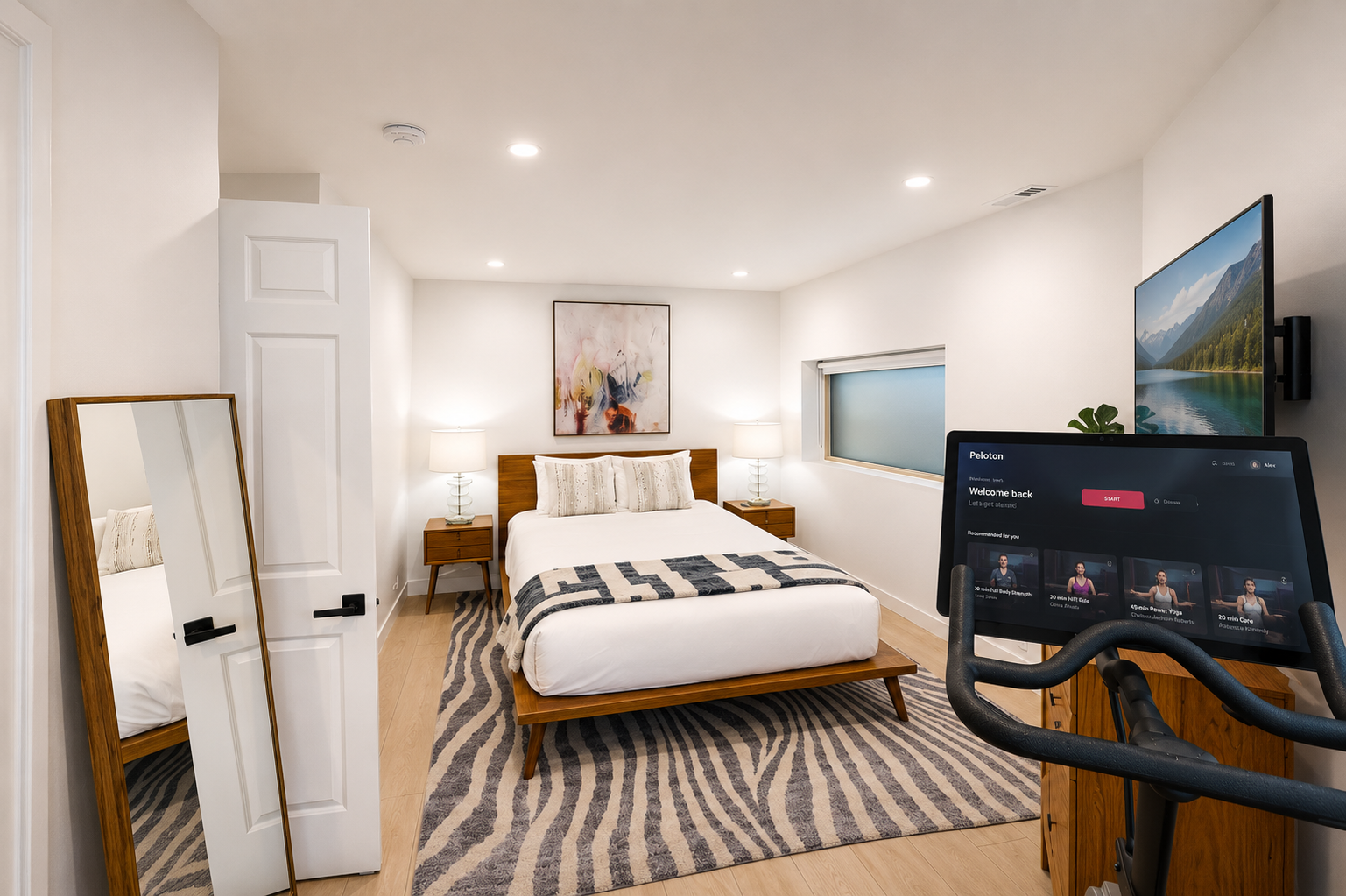 Your serene bedroom features warm wood furnishings, a plush bed, art above, and modern amenities—including a Peloton to energize your stay.