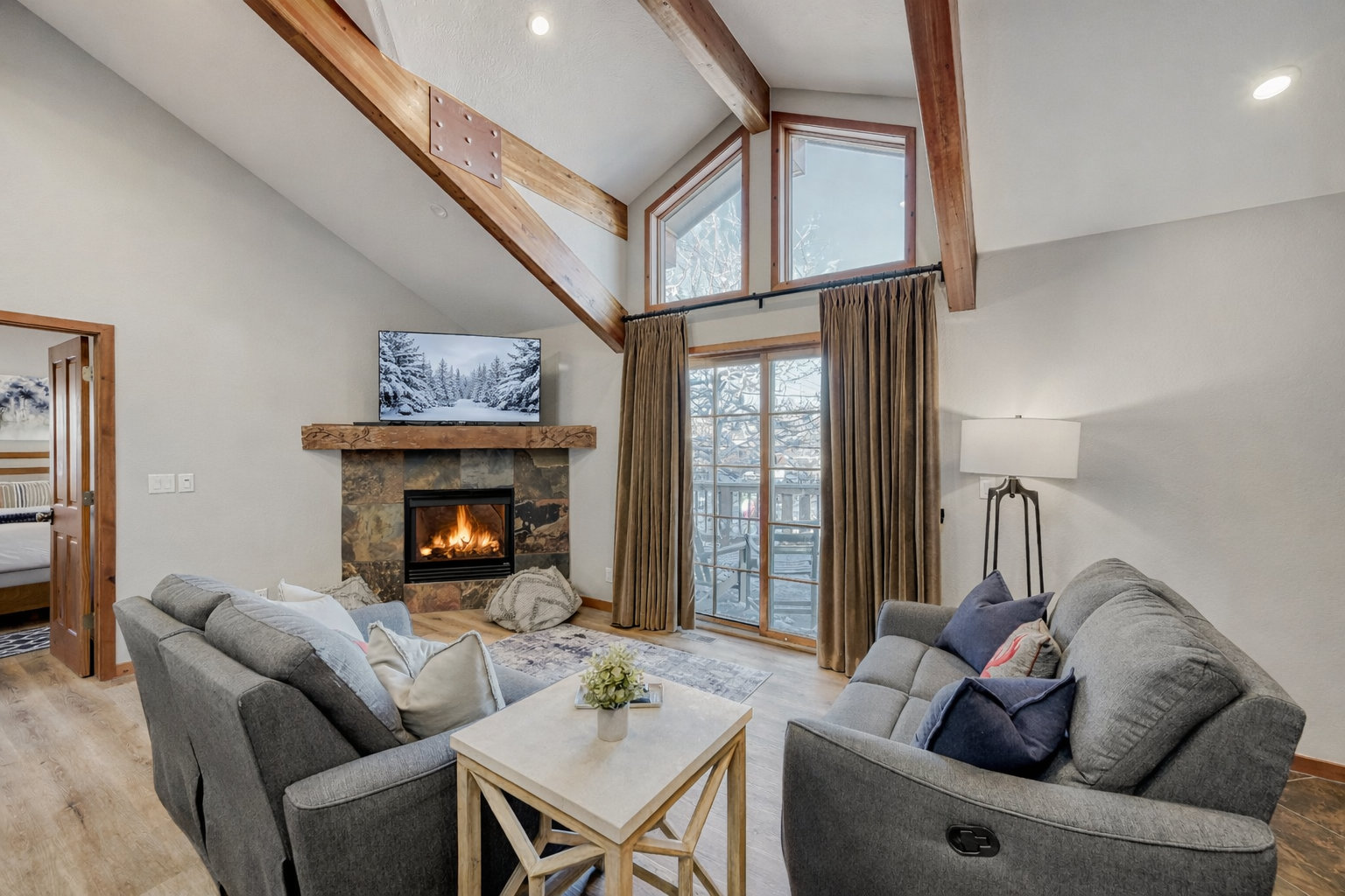 Cozy up in this mountain-modern living room featuring stone fireplace, vaulted ceilings, and comfortable seating.
