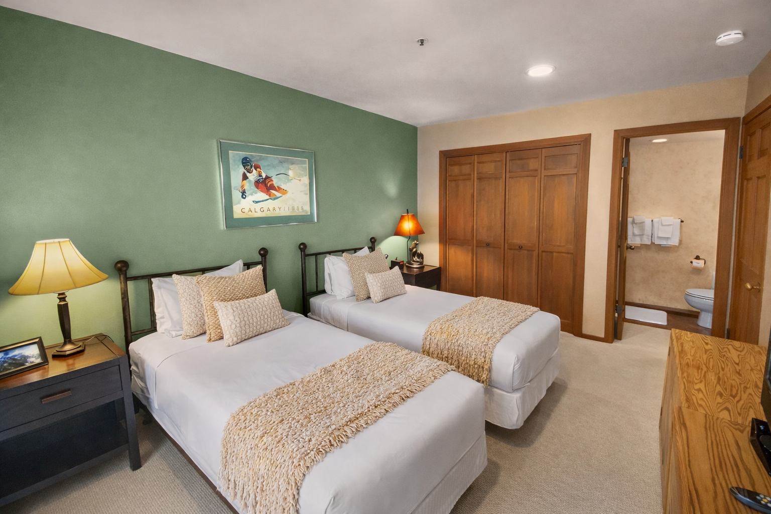 Unwind in your cozy twin bedroom with plush bedding and warm mountain-inspired decor, featuring an ensuite bathroom for your convenience.