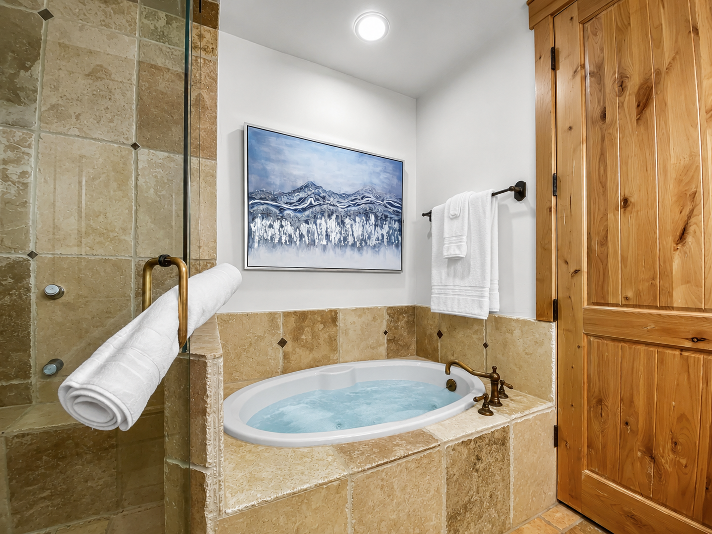Sink into the deep soaking tub after a day of adventure, surrounded by warm stone tile and rustic wood finishes that create a cozy mountain retreat ambiance.