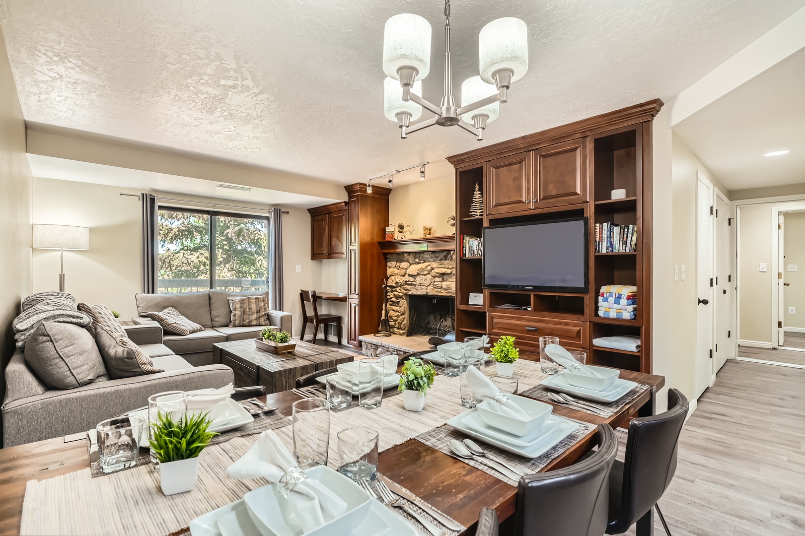 Gather around the rustic dining table for memorable meals, then unwind on plush seating by the stone fireplace, all within your inviting open-concept living space bathed in natural light.