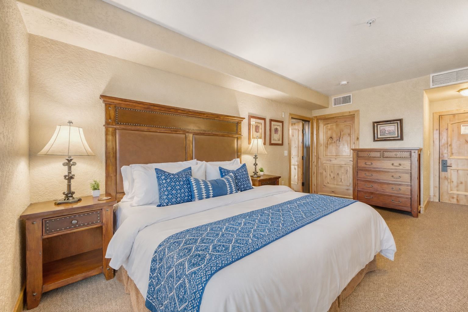 Relax in this spacious master suite featuring a king bed and handcrafted wood furniture. A serene retreat designed for ultimate comfort and a restful night's sleep.