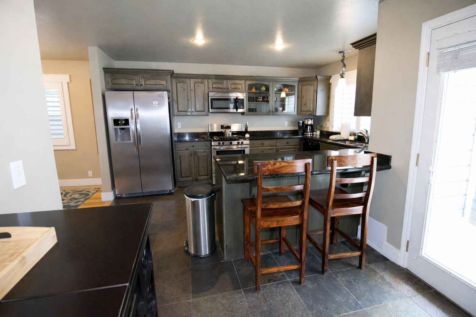 Prepare gourmet meals in this modern wrap-around kitchen. It features sleek stainless steel appliances, including a side-by-side refrigerator, and a convenient breakfast bar with rustic wooden seating